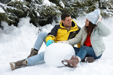 Photo of Happy couple with ball for snowman outdoors. Winter vacation