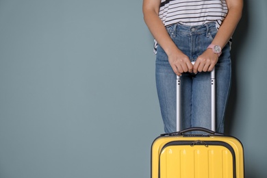 Woman with bright yellow suitcase on color background