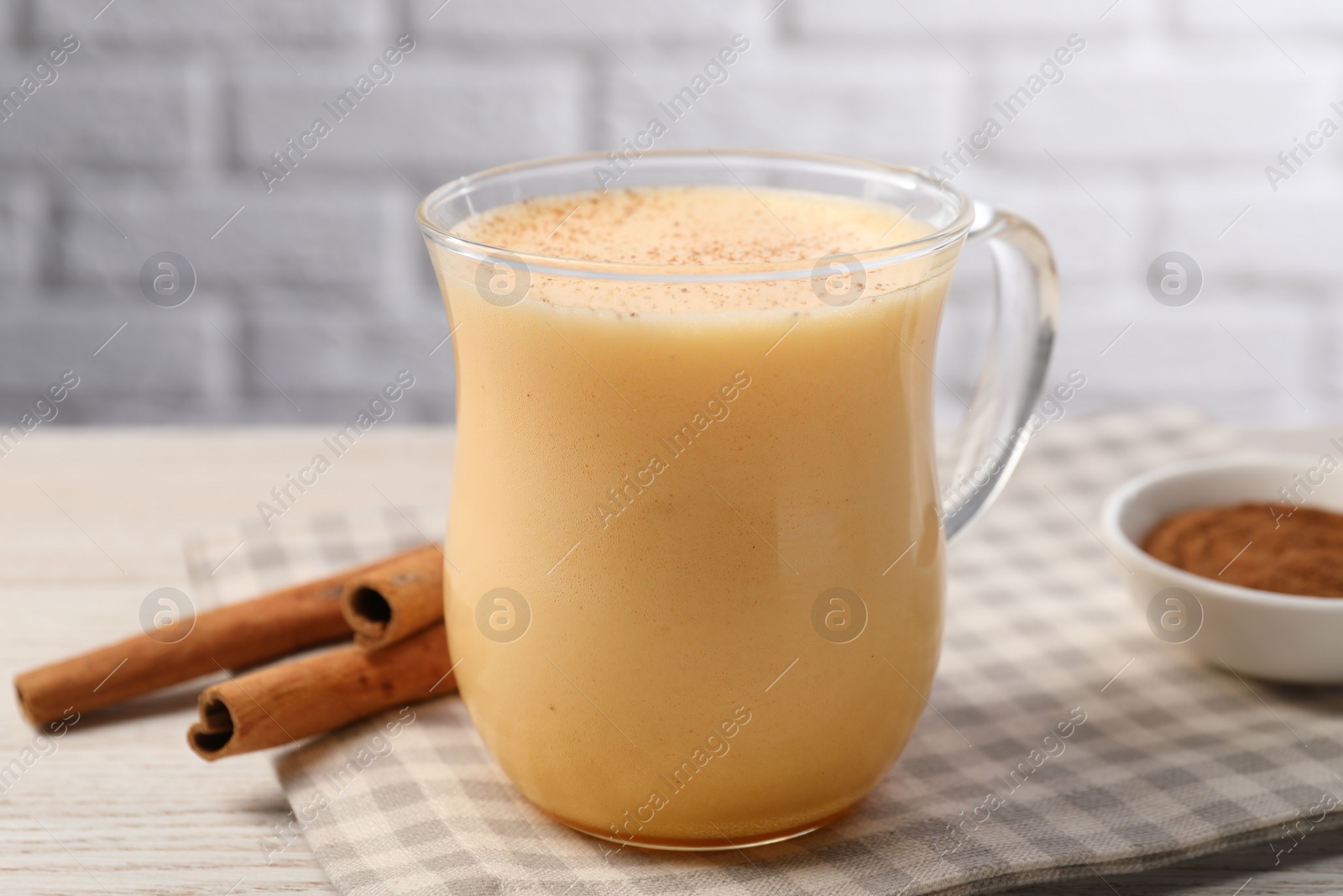 Photo of Delicious eggnog with cinnamon on wooden table, closeup