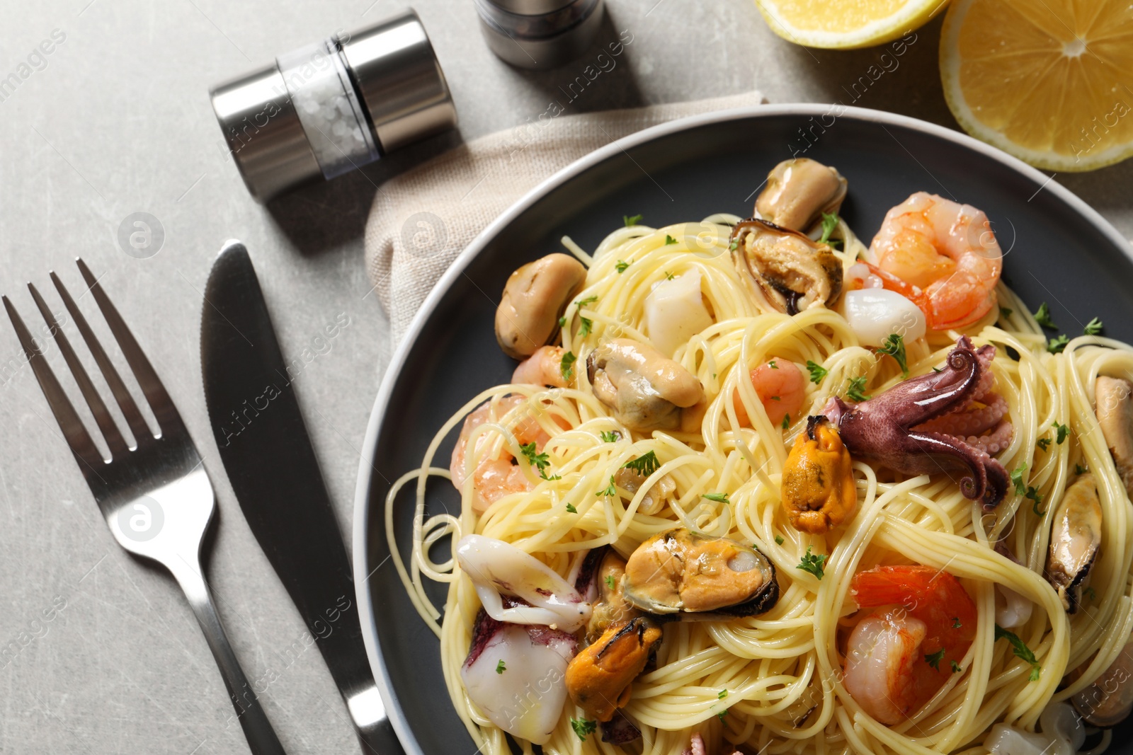 Photo of Delicious pasta with sea food served on grey table, flat lay