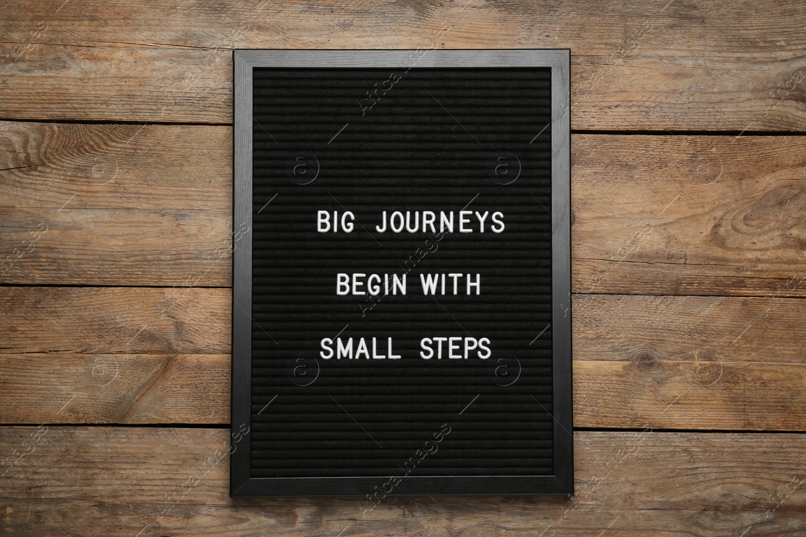 Photo of Black letter board with motivational quote Big Journey Begin with Small Steps on wooden background, top view