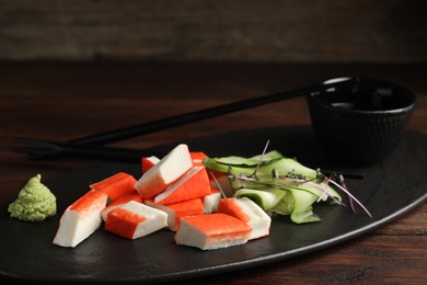 Fresh crab sticks with cucumber served on dark table, closeup