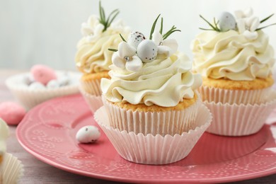 Photo of Tasty Easter cupcakes with vanilla cream on table, closeup