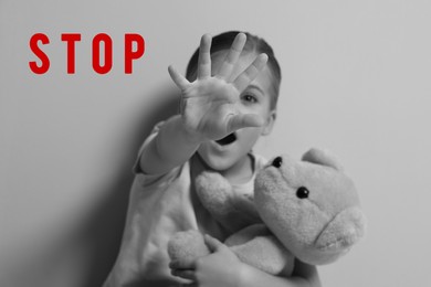 Image of No child abuse. Girl with toy making stop gesture, selective focus. Black and white effect