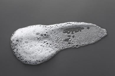 Photo of Smudge of white washing foam on dark gray background, top view