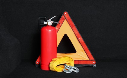 Photo of Red fire extinguisher, towing strap and foldable emergency warning triangle in trunk. Car safety