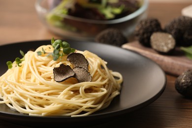 Photo of Tasty spaghetti with truffle on wooden table, closeup