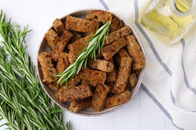 Crispy rusks with rosemary on white tiled table, flat lay