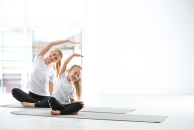 Mother and daughter in matching sportswear doing yoga together at home