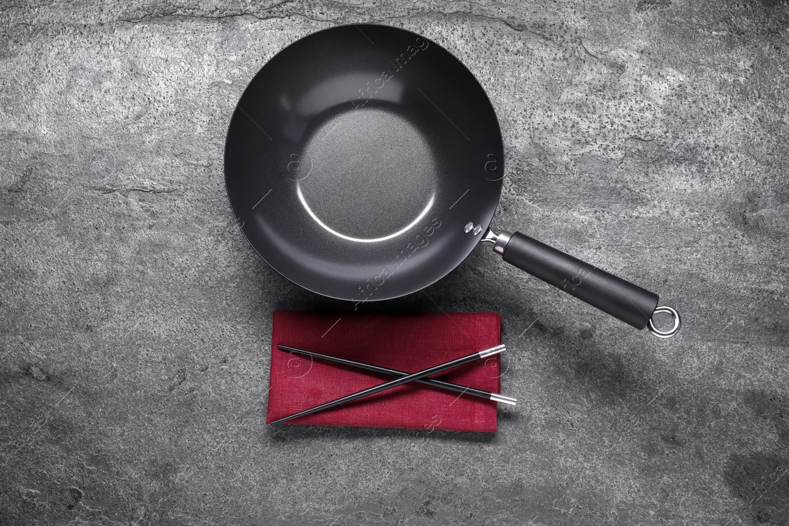 Photo of Empty iron wok and chopsticks on grey table, flat lay