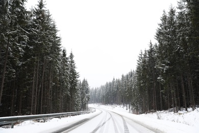 Beautiful landscape with conifer forest and road on snowy winter day