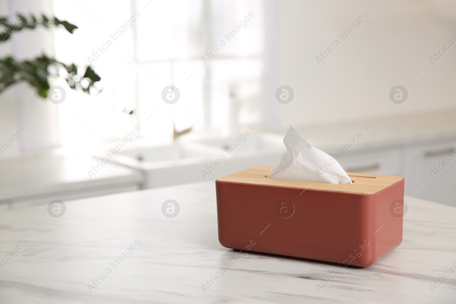 Photo of Box with paper tissues on white marble table in kitchen. Space for text