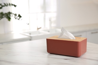 Photo of Box with paper tissues on white marble table in kitchen. Space for text