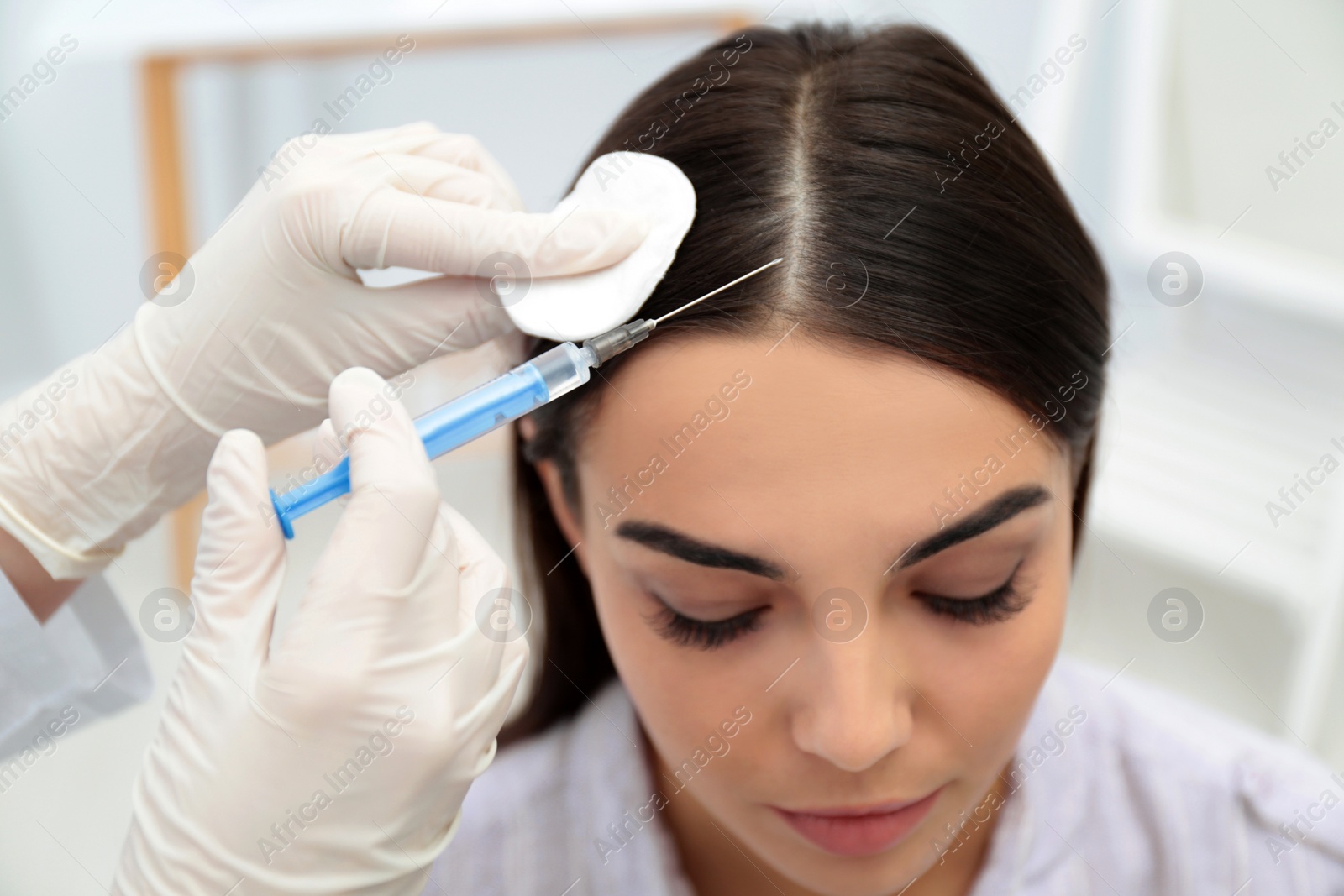 Photo of Young woman with hair loss problem receiving injection in salon
