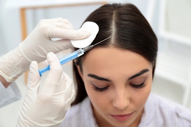 Photo of Young woman with hair loss problem receiving injection in salon