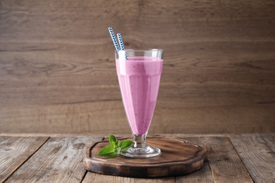 Photo of Tasty milk shake in glass on wooden table