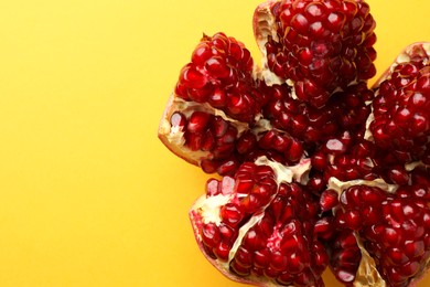 Photo of Cut fresh pomegranate on yellow background, top view. Space for text