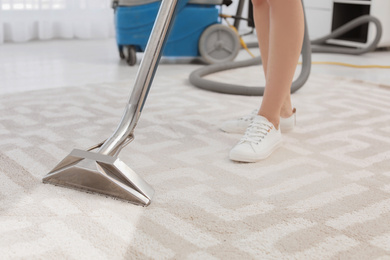 Female worker removing dirt from carpet indoors, closeup. Cleaning service 