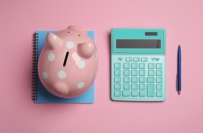 Photo of Calculator, piggy bank, notebook and pen on pink background, flat lay