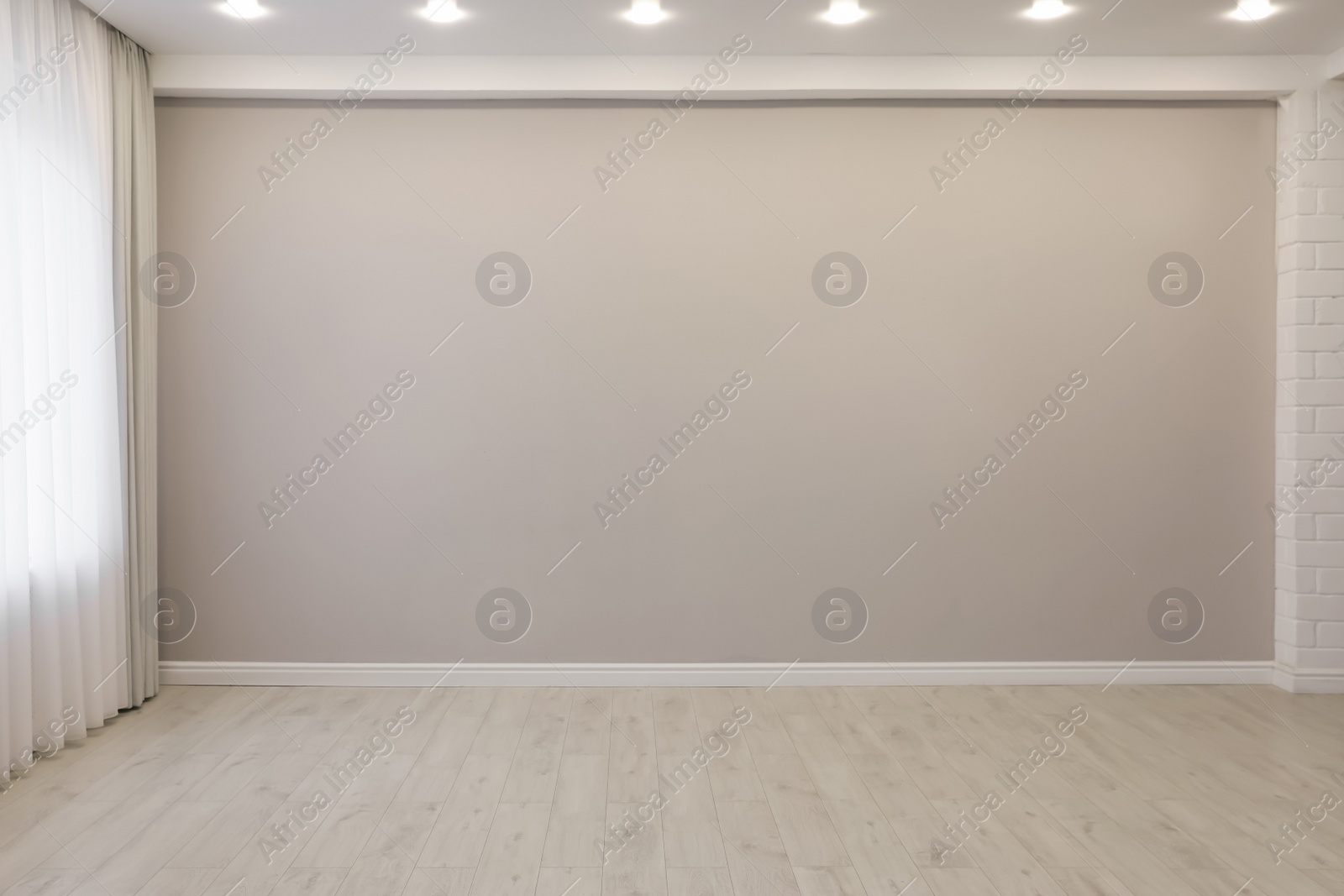 Photo of Empty room with beige wall, large window and wooden floor