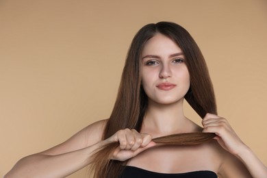 Photo of Young woman with strong healthy hair on beige background