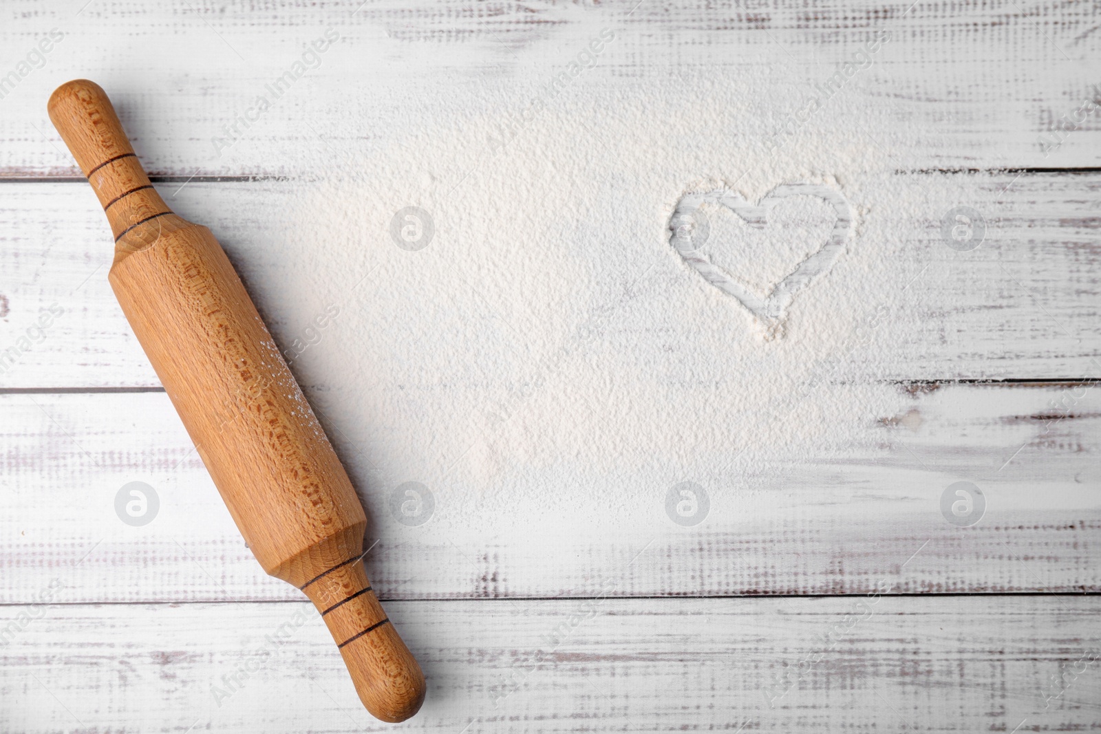 Photo of Flour and rolling pin on white wooden table, top view