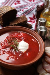 Photo of Clay bowl with Ukrainian borsch served on table