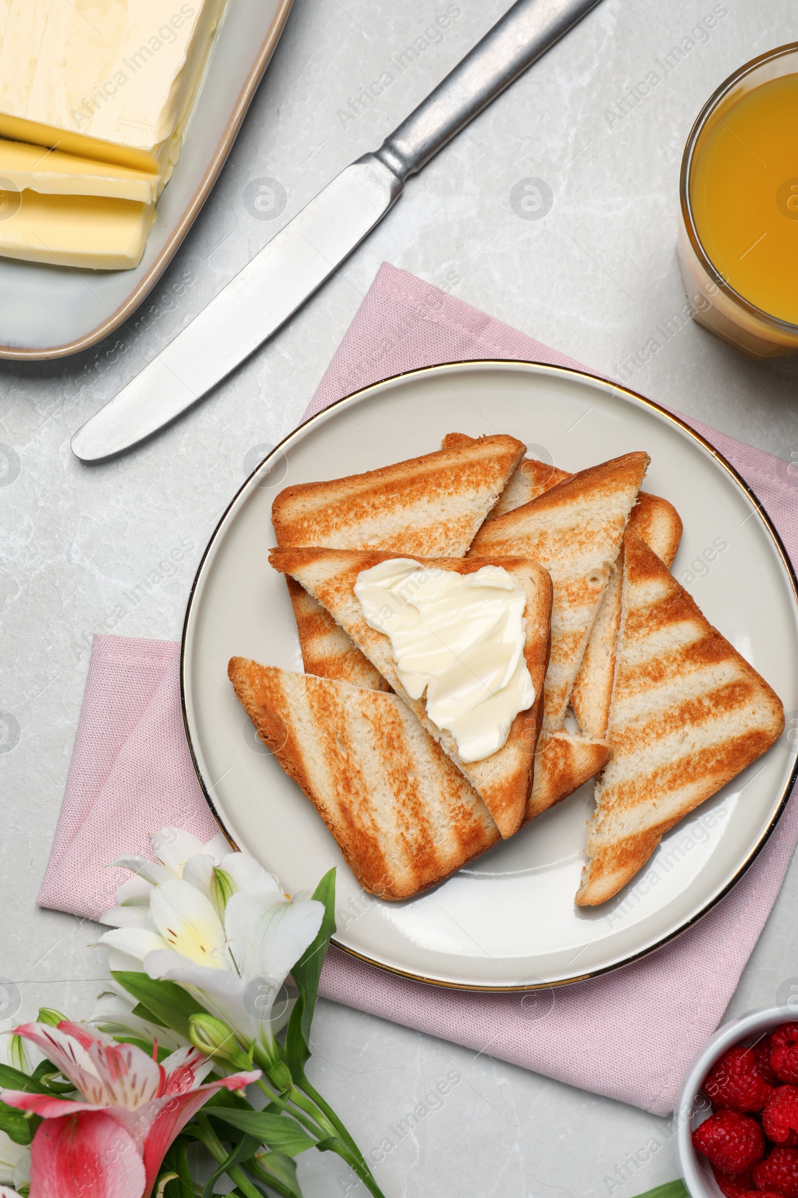Photo of Tasty toasts served with spreading butter and honey on light grey table, flat lay