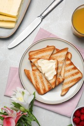 Photo of Tasty toasts served with spreading butter and honey on light grey table, flat lay