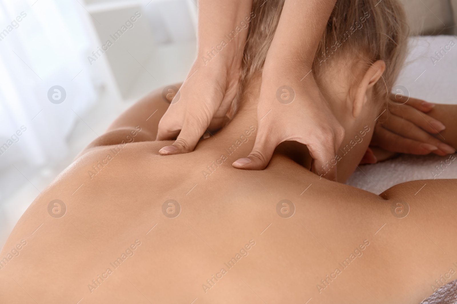 Photo of Relaxed woman receiving neck massage in wellness center