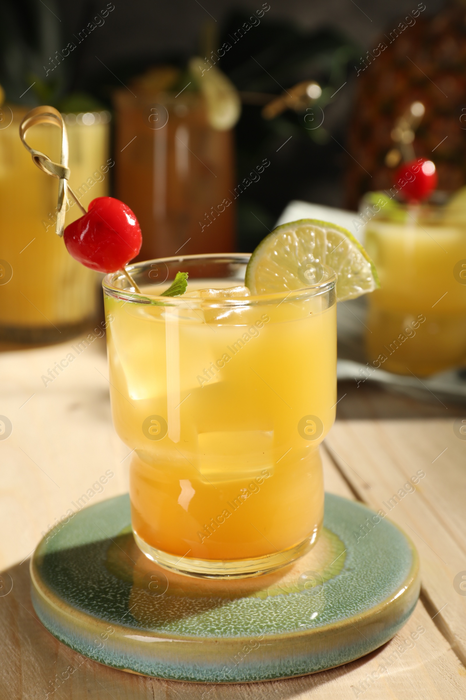 Photo of Tasty pineapple cocktail with cherry and lime on wooden table