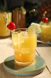 Photo of Tasty pineapple cocktail with cherry and lime on wooden table