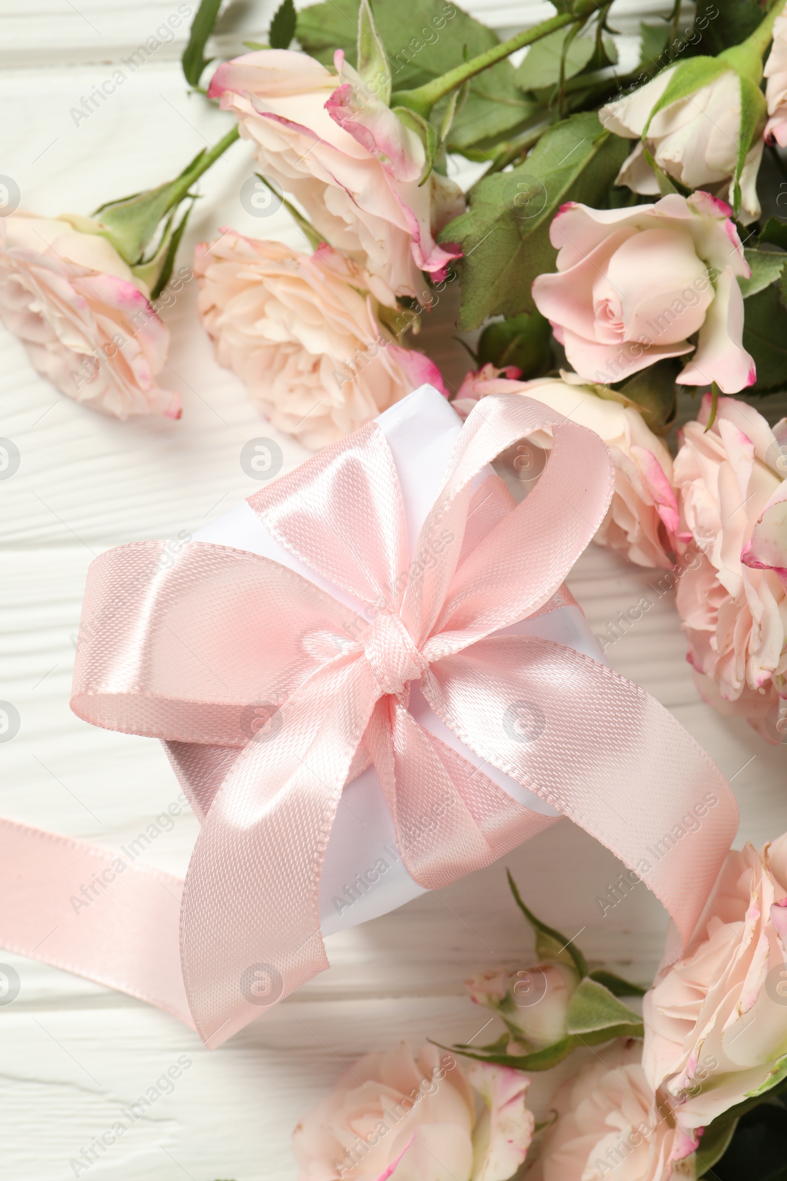 Photo of Happy Mother's Day. Beautiful roses and gift box on white wooden table, flat lay