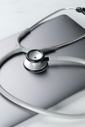 Photo of Modern laptop and stethoscope on white table