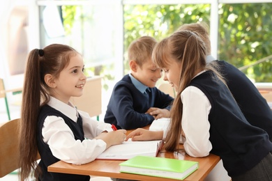 Photo of Little children in classroom. Stylish school uniform