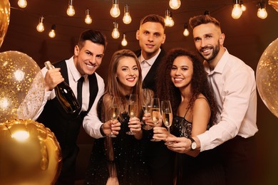 Photo of Happy friends with glasses of sparkling wine celebrating New Year indoors