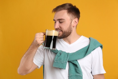 Handsome man with cold kvass on yellow background. Traditional Russian summer drink