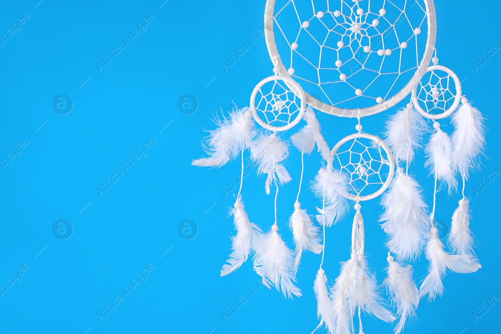 Photo of Beautiful handmade dream catcher on light blue background. Space for text