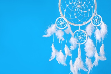 Photo of Beautiful handmade dream catcher on light blue background. Space for text