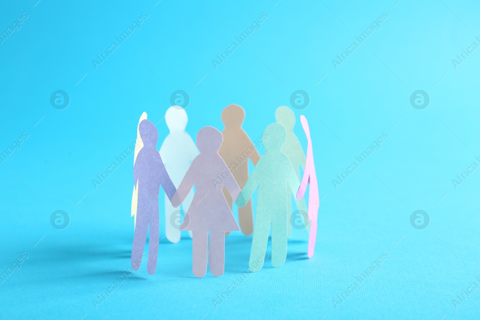 Photo of Paper human figures making circle on turquoise background. Diversity and Inclusion concept