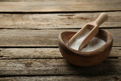 Baking powder in bowl and scoop on wooden table, space for text