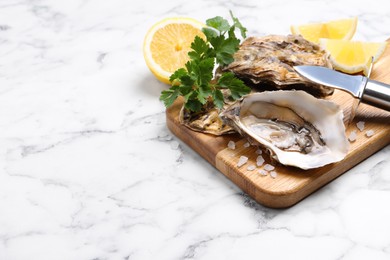Photo of Fresh oysters with lemon, parsley and knife on white marble table, space for text