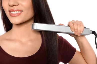 Happy woman using hair iron on white background, closeup