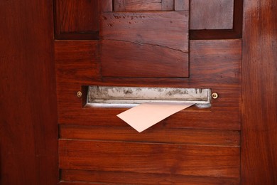 Mail slot with envelope in wooden door