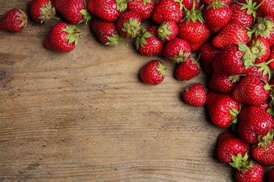 Delicious ripe strawberries on wooden table, flat lay. Space for text