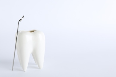 Photo of Tooth shaped holder and dentist mirror on white background. Space for text