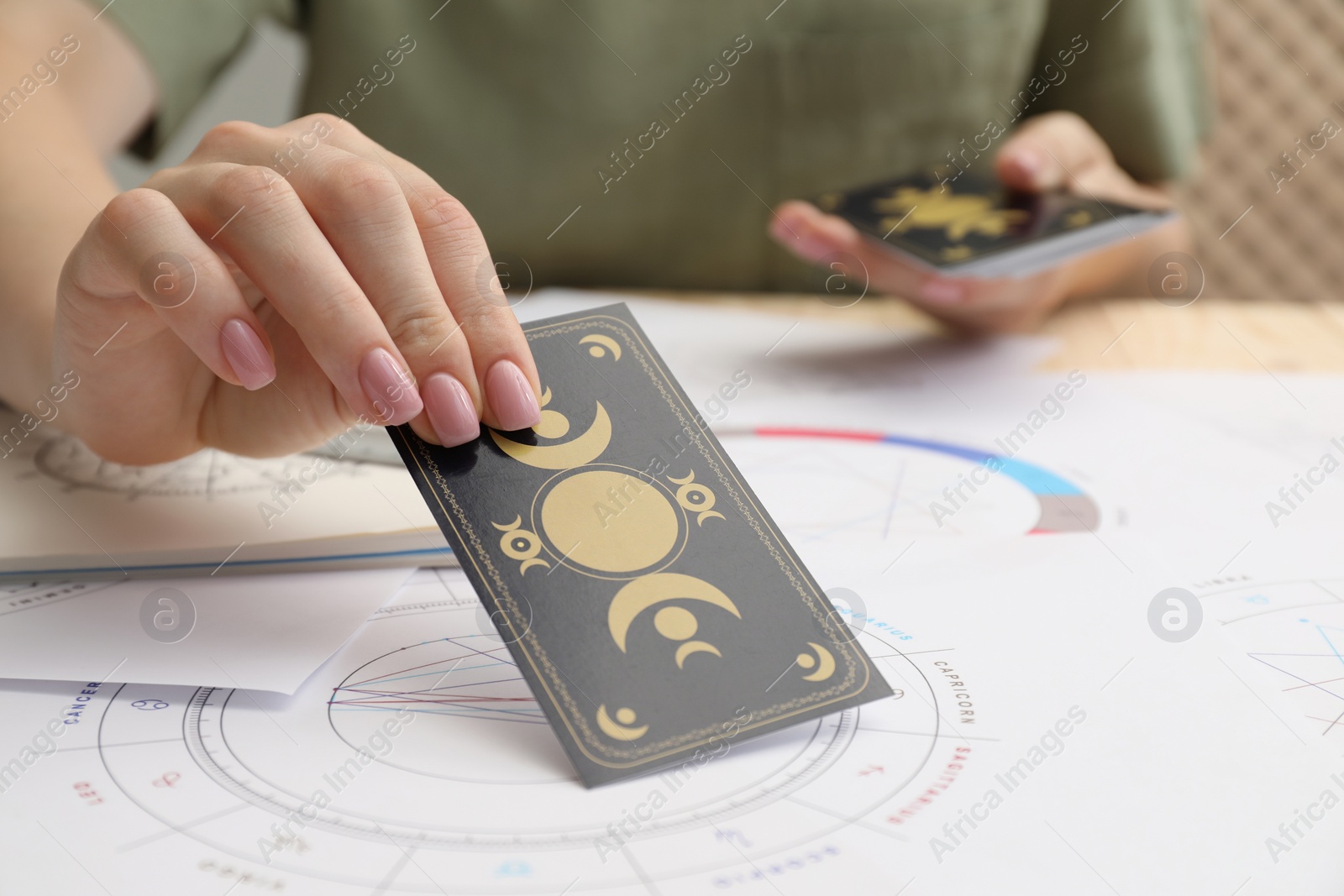 Photo of Woman using tarot cards at table, closeup. Astrological predictions