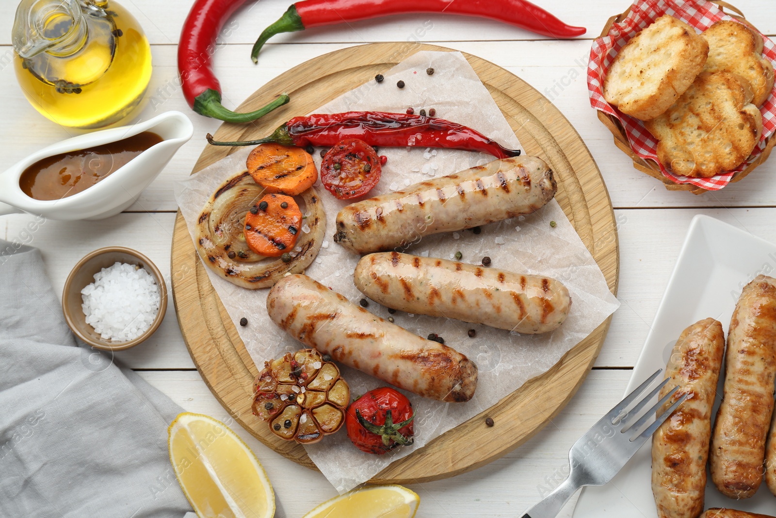 Photo of Tasty grilled sausages served on white wooden table, flat lay