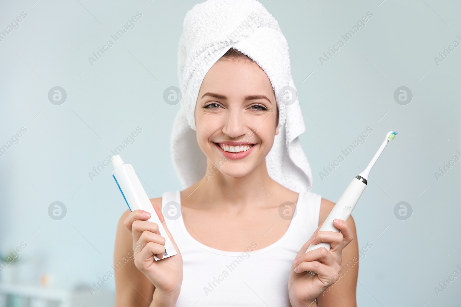 Photo of Portrait of young woman with electric toothbrush and paste on blurred background