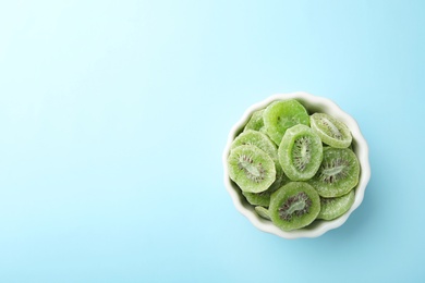 Bowl of dried kiwi on color background, top view with space for text. Tasty and healthy fruit